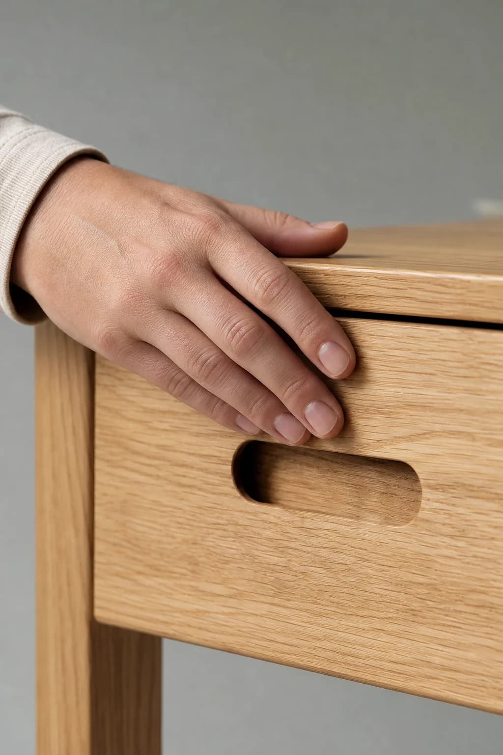 Hand resting on an oiled light oak drawer front